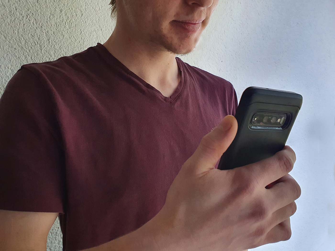 Junger Mann hält ein Smartphone in der Hand